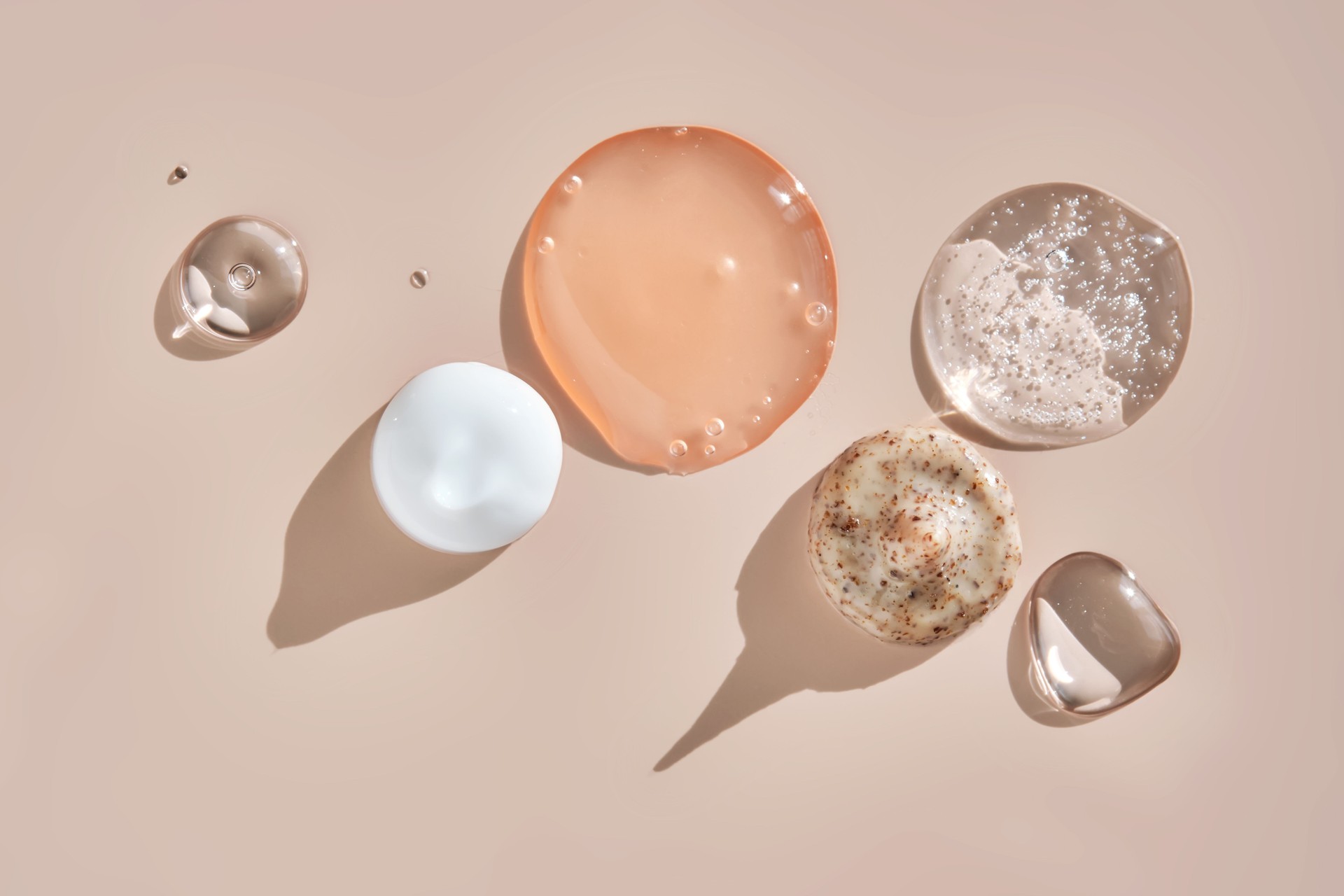 Several cosmetic products on a pink background.